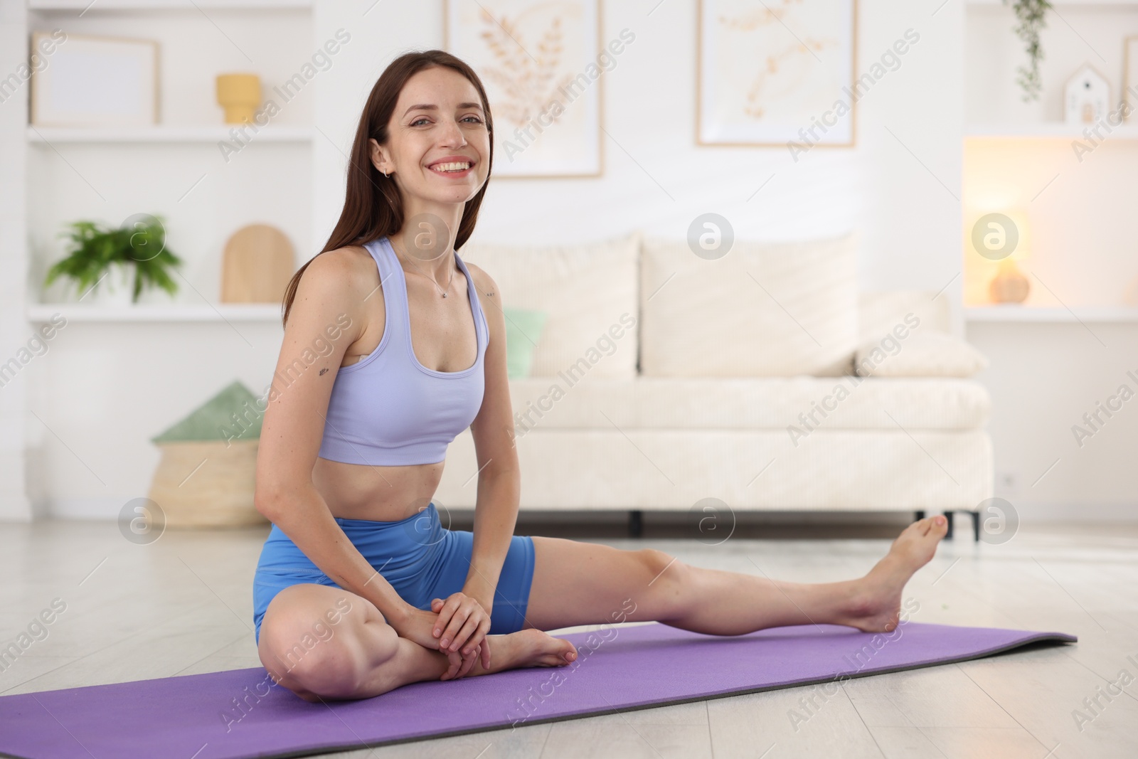 Smiling woman in sportswear stretching on mat at home Photo of Smiling woman in sportswear stretching on mat at home