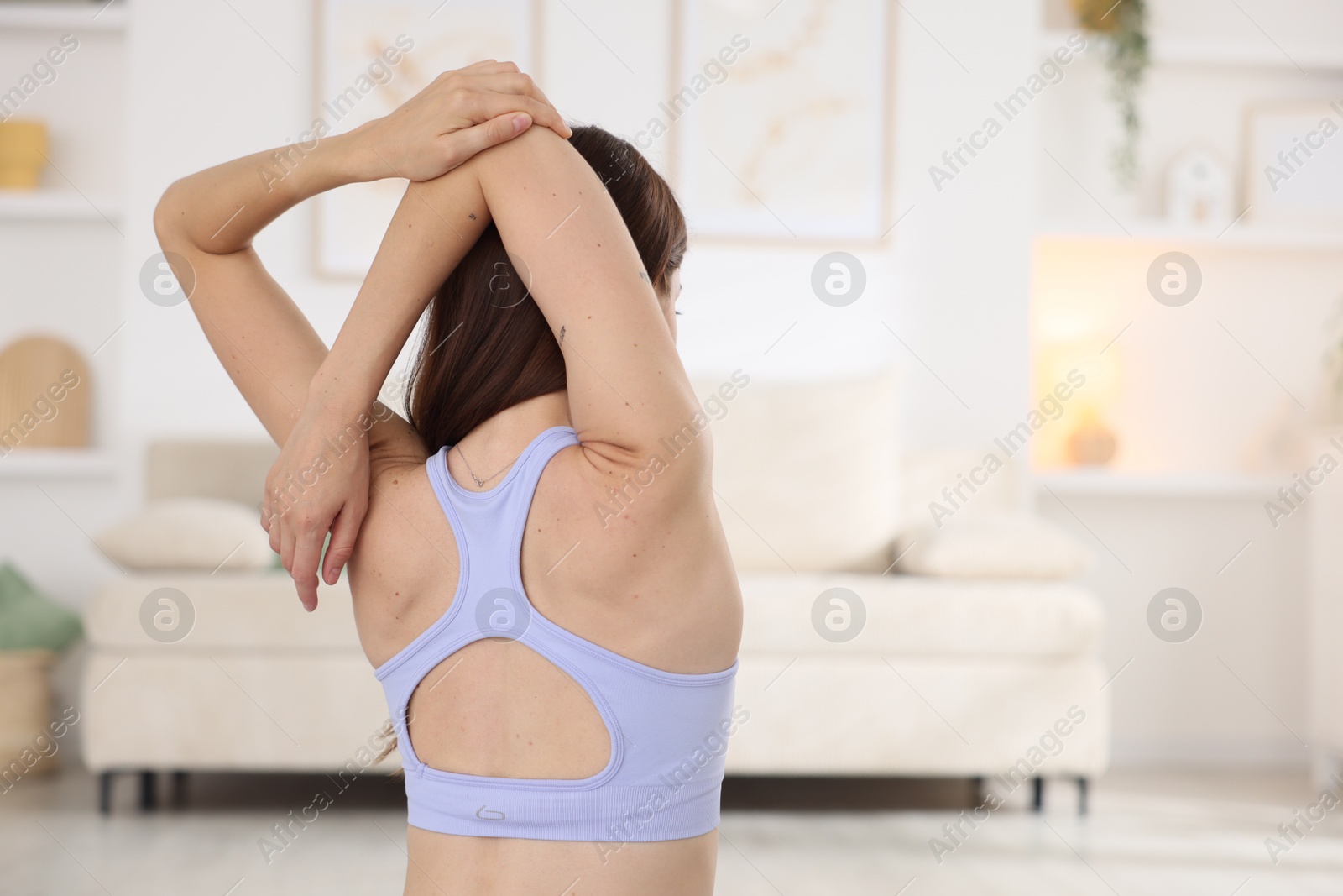 Woman in sportswear stretching at home, back view Photo of Woman in sportswear stretching at home, back view