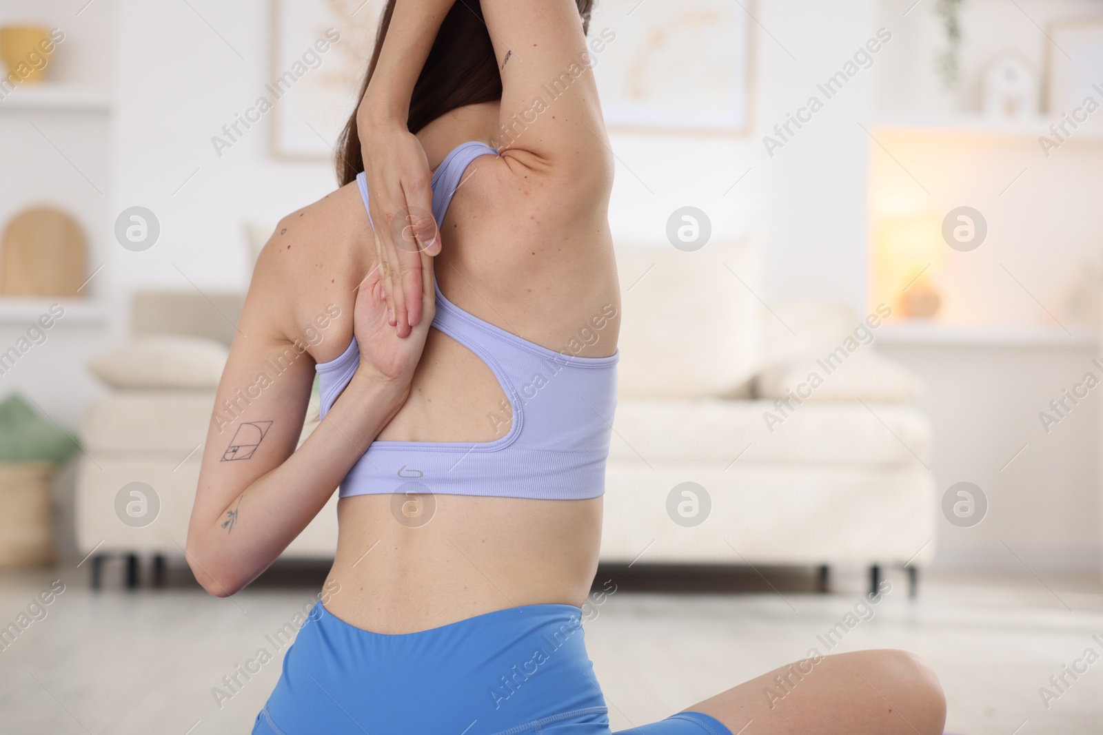 Woman in sportswear stretching at home, back view Photo of Woman in sportswear stretching at home, back view