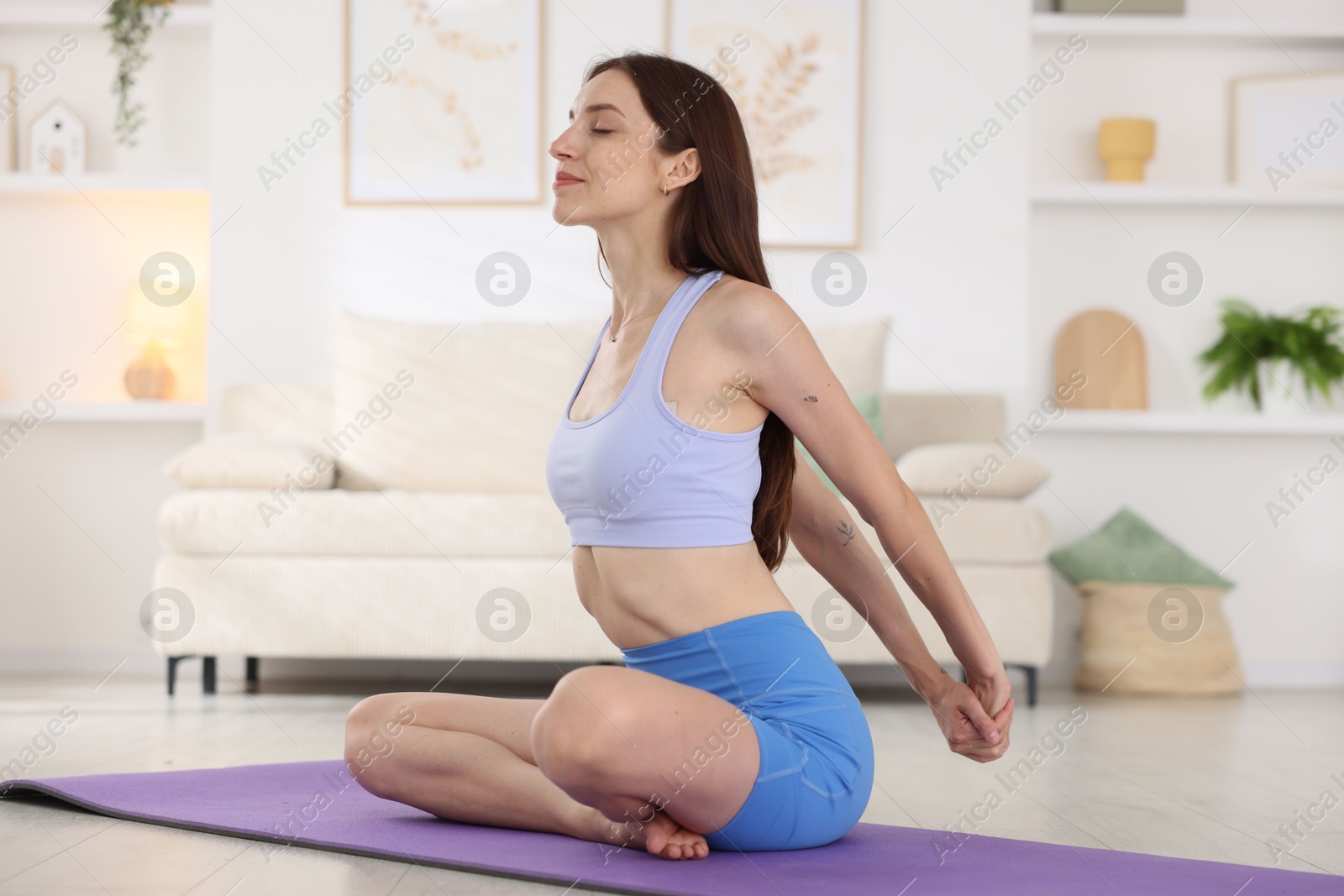 Young woman in sportswear stretching on mat at home Photo of Young woman in sportswear stretching on mat at home