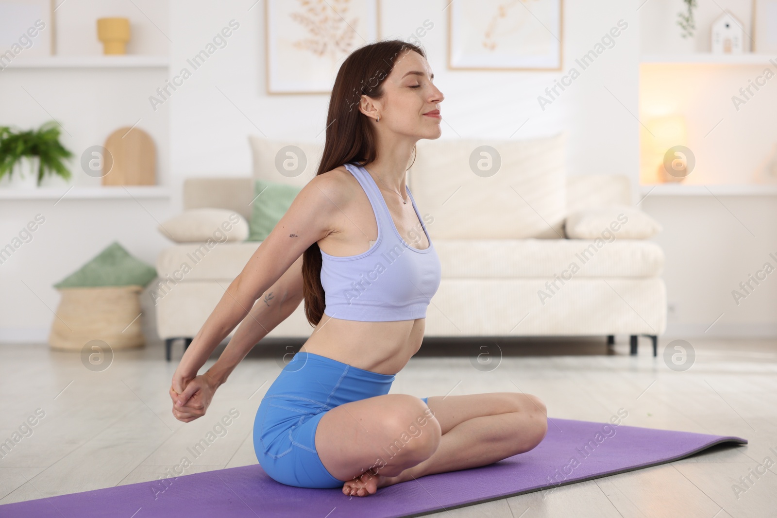 Young woman in sportswear stretching on mat at home Photo of Young woman in sportswear stretching on mat at home