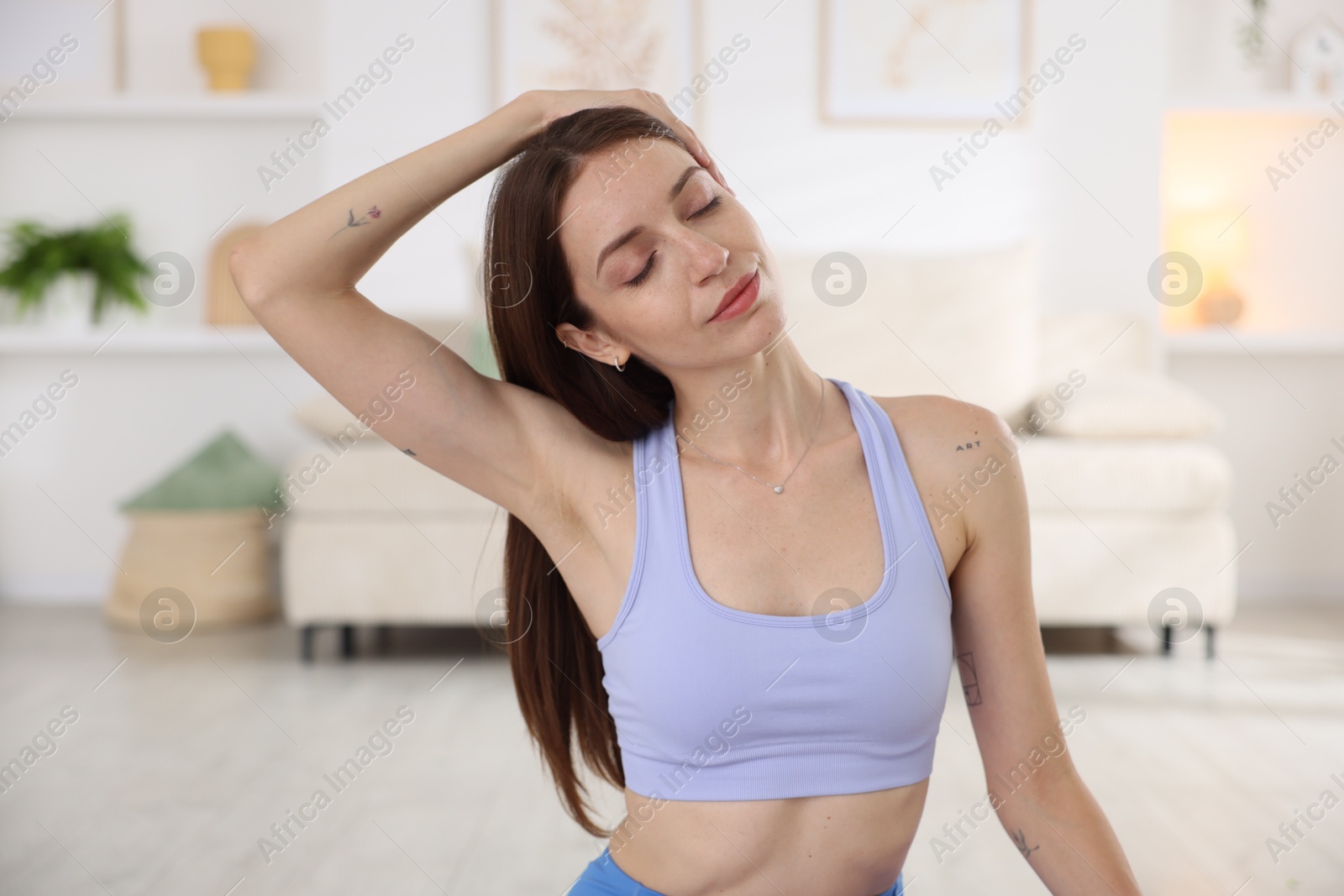 Young woman in sportswear stretching at home Photo of Young woman in sportswear stretching at home