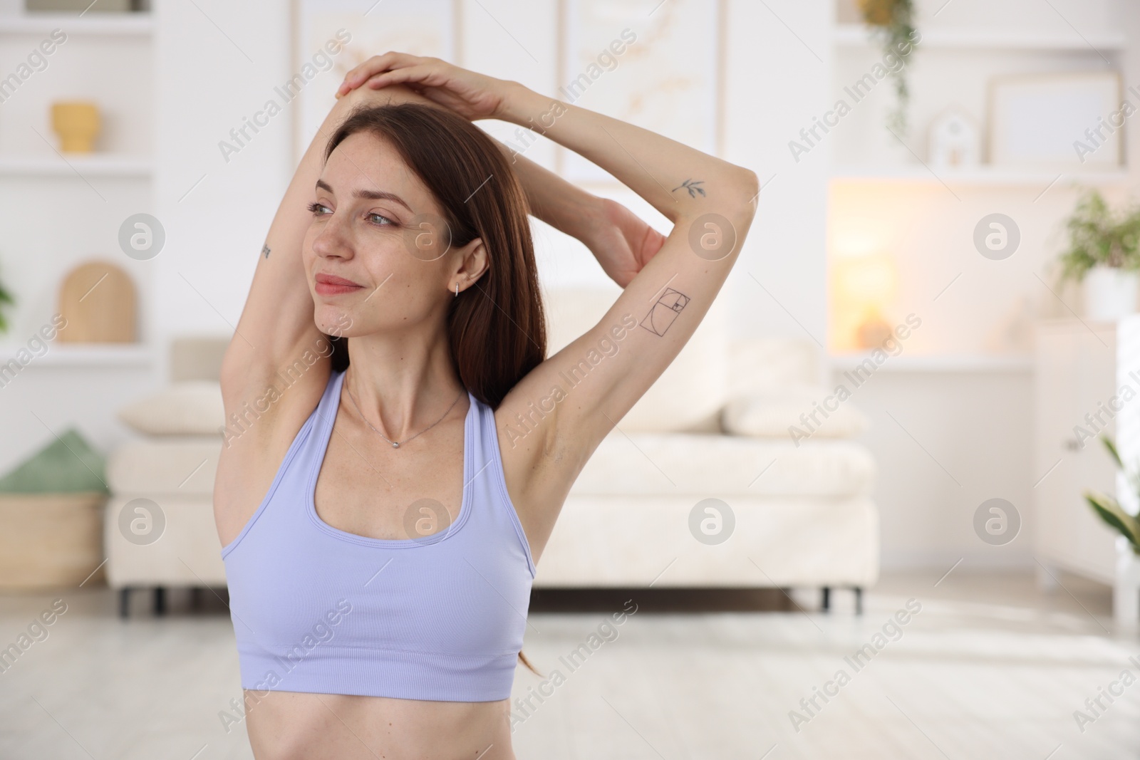 Young woman in sportswear stretching at home Photo of Young woman in sportswear stretching at home
