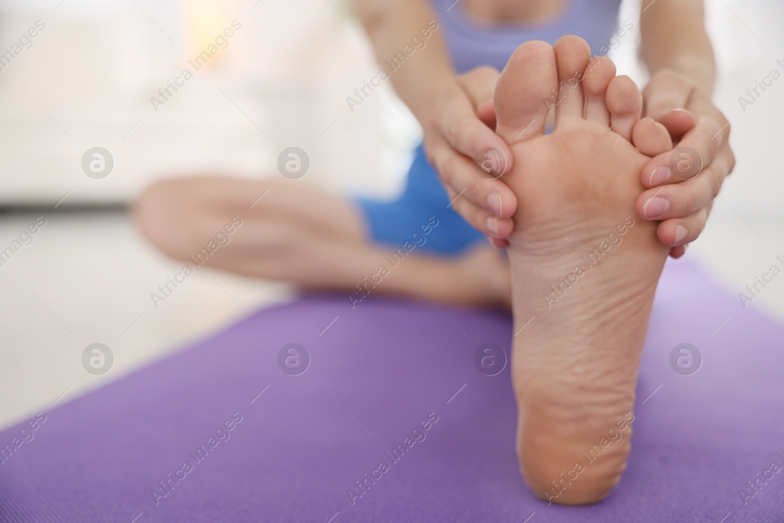 Woman stretching on mat at home, closeup Photo of Woman stretching on mat at home, closeup