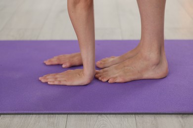 Photo of Woman stretching on mat at home, closeup