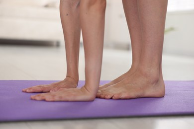 Photo of Woman stretching on mat at home, closeup