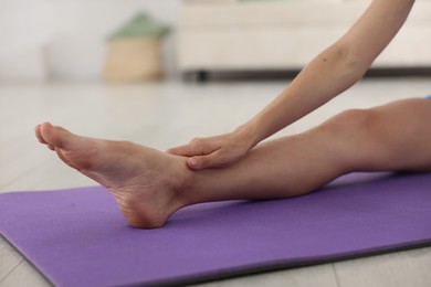 Photo of Woman stretching on mat at home, closeup