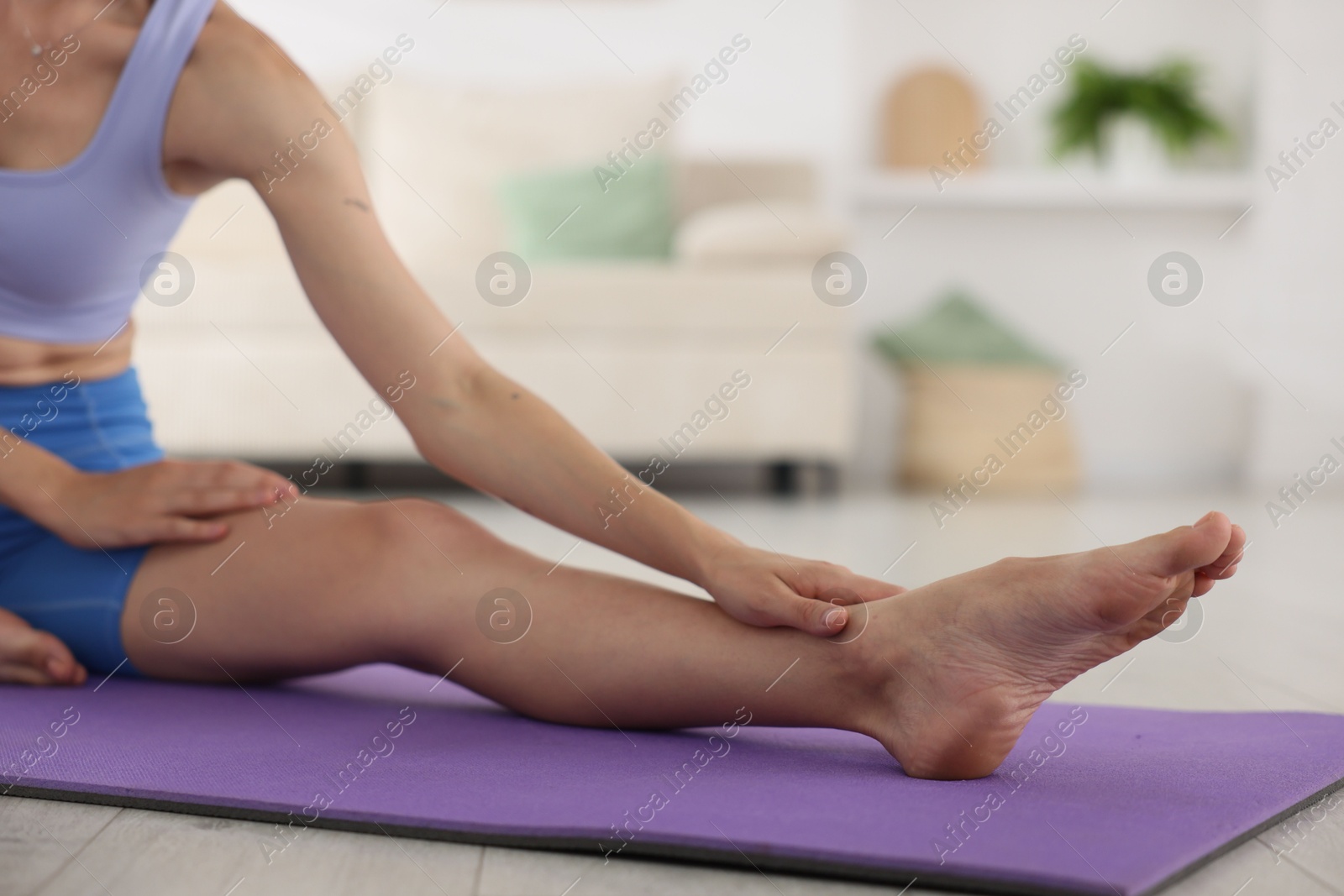 Woman stretching on mat at home, closeup Photo of Woman stretching on mat at home, closeup