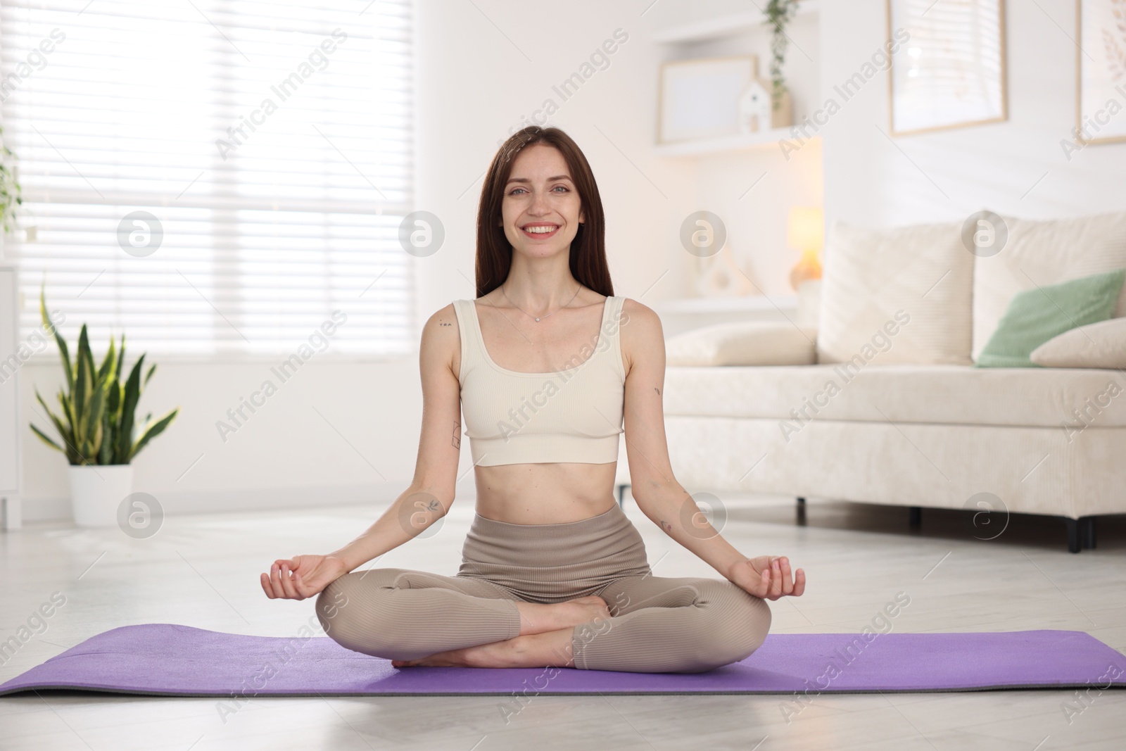 Smiling woman in sportswear practicing yoga on mat at home Photo of Smiling woman in sportswear practicing yoga on mat at home