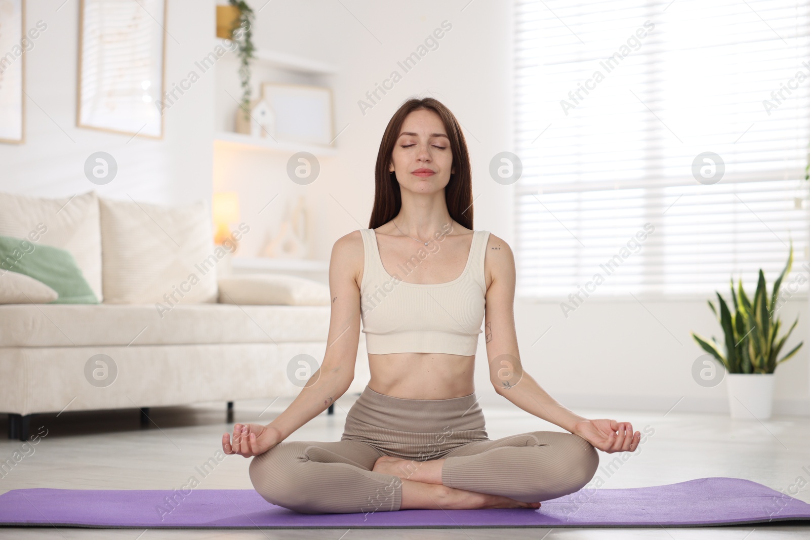 Young woman in sportswear practicing yoga on mat at home Photo of Young woman in sportswear practicing yoga on mat at home