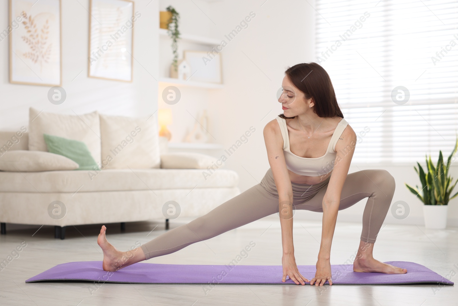 Young woman in sportswear stretching on mat at home Photo of Young woman in sportswear stretching on mat at home