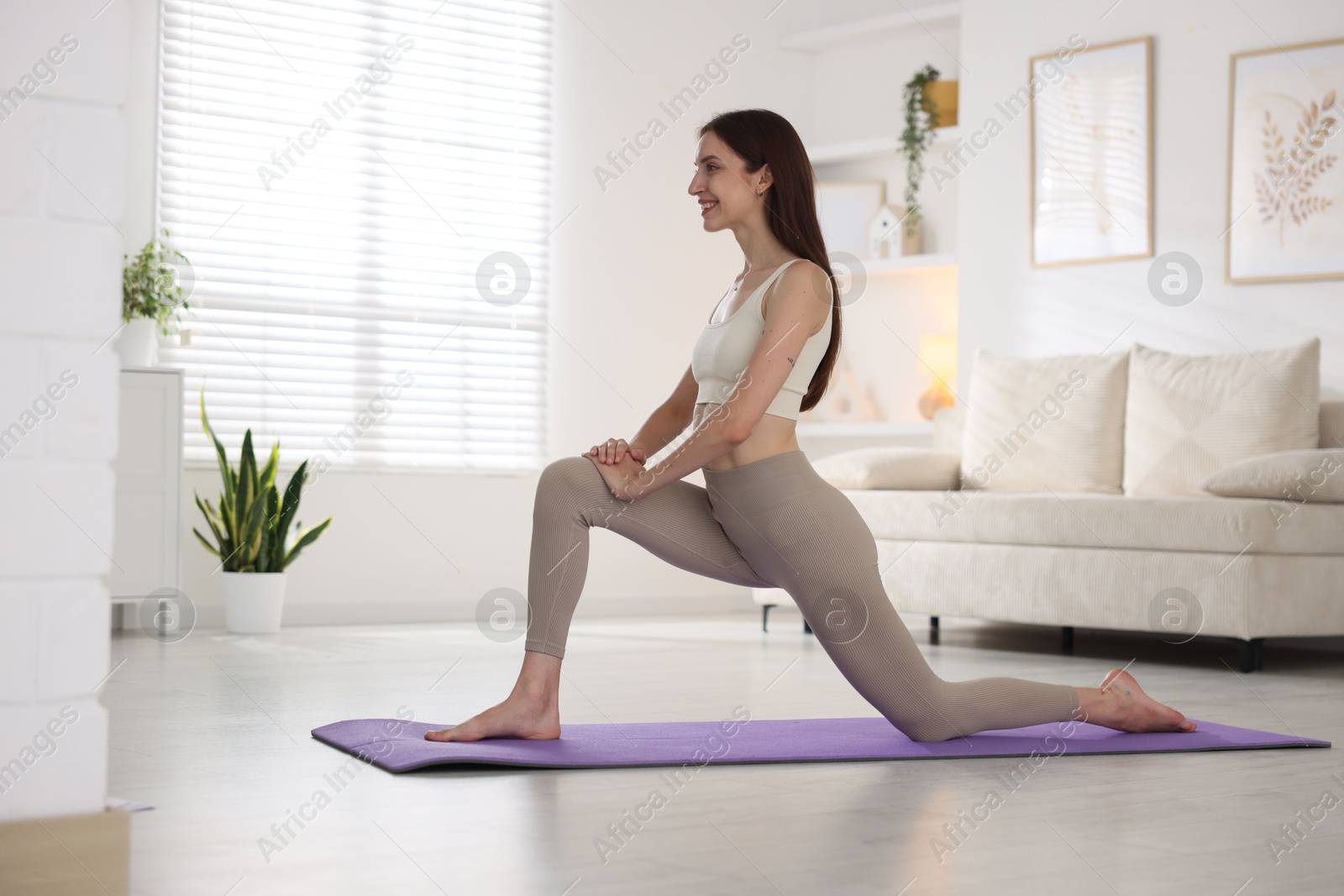 Smiling woman in sportswear stretching on mat at home Photo of Smiling woman in sportswear stretching on mat at home