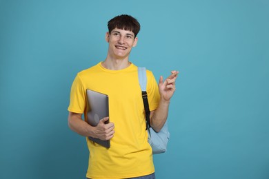 Photo of Happy student crossing fingers for good exam result on light blue background