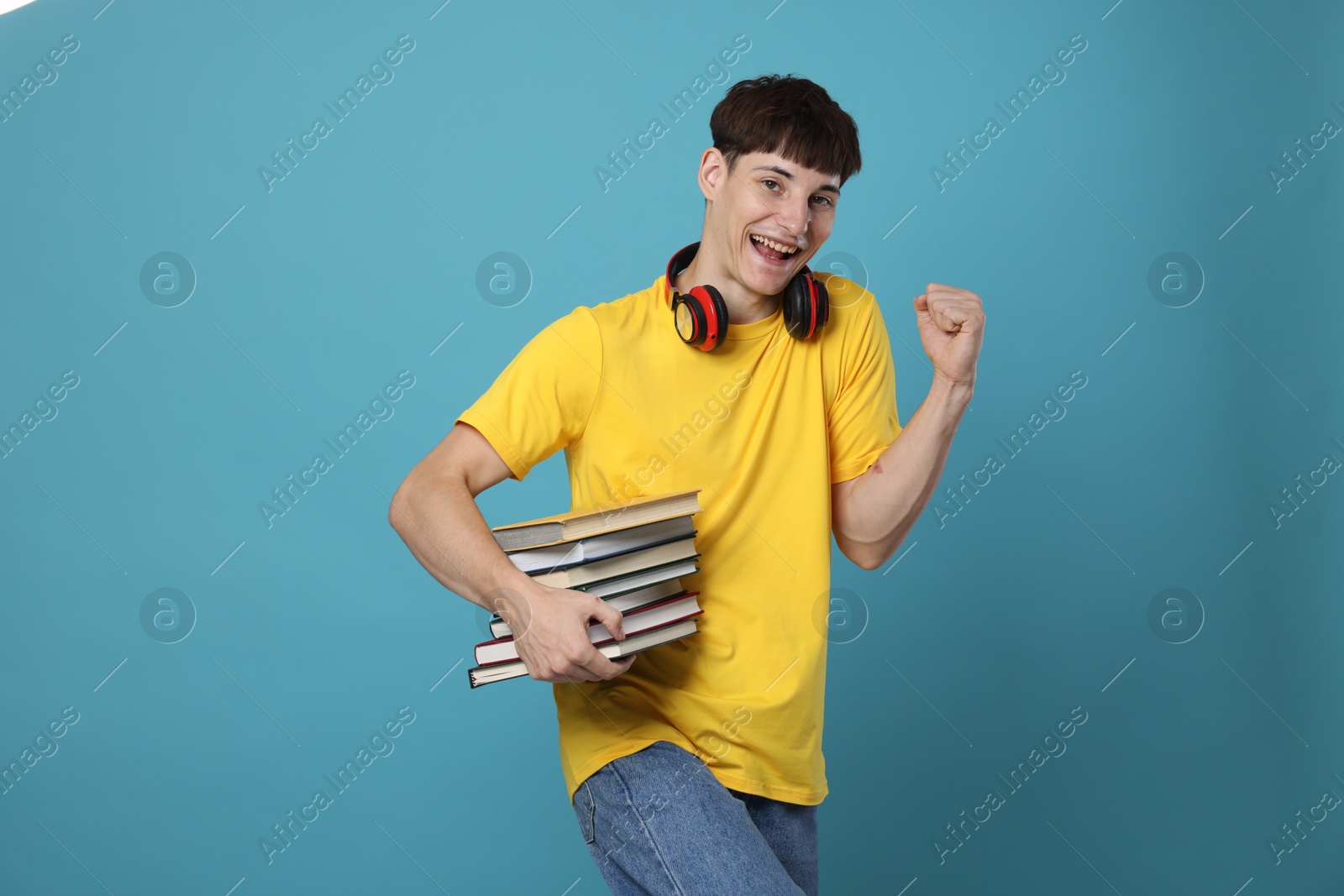 Happy student with books celebrating good exam result on light blue background Photo of Happy student with books celebrating good exam result on light blue background
