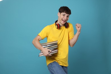 Photo of Happy student with books celebrating good exam result on light blue background