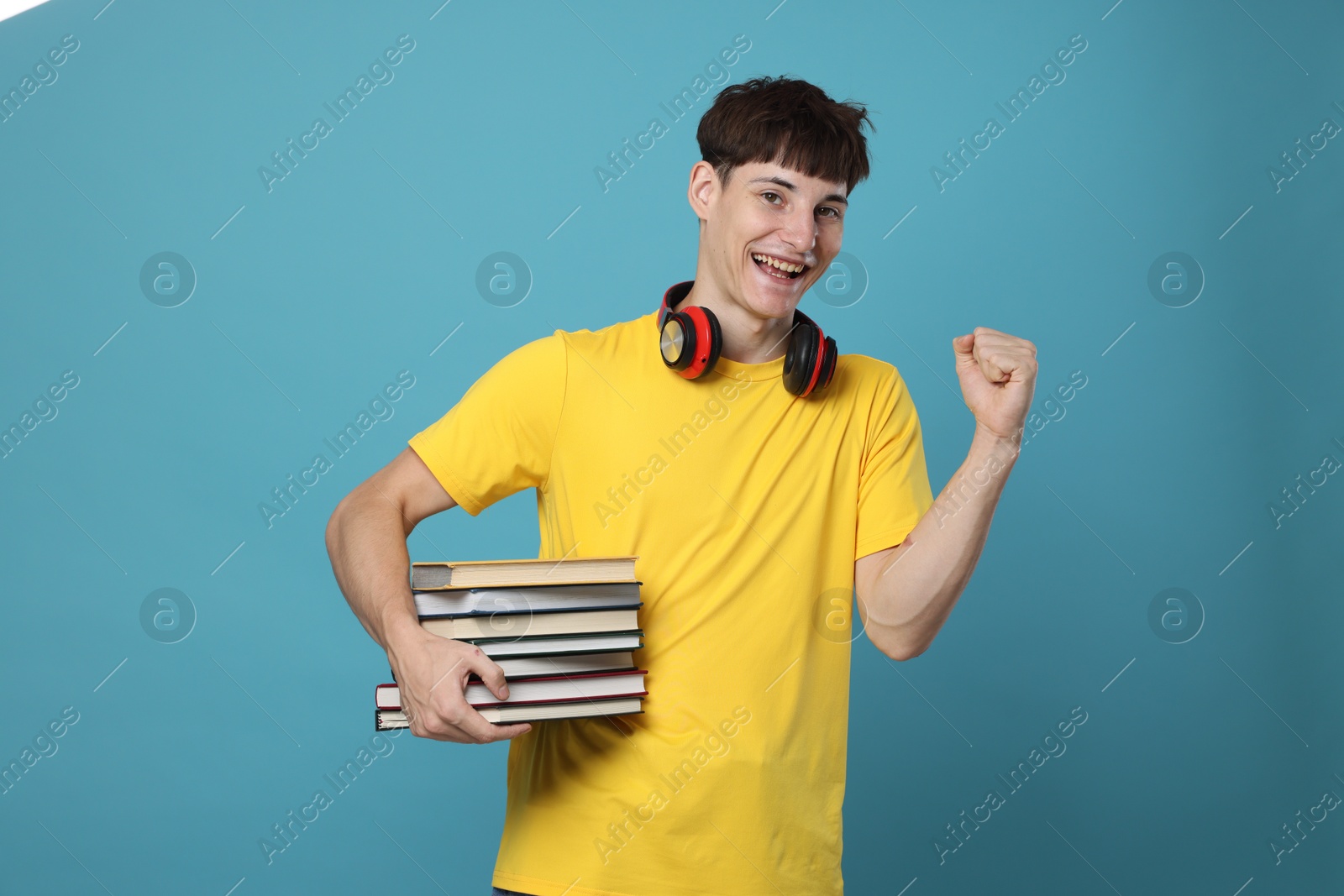 Happy student with books celebrating good exam result on light blue background Photo of Happy student with books celebrating good exam result on light blue background
