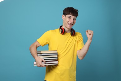Photo of Happy student with books celebrating good exam result on light blue background