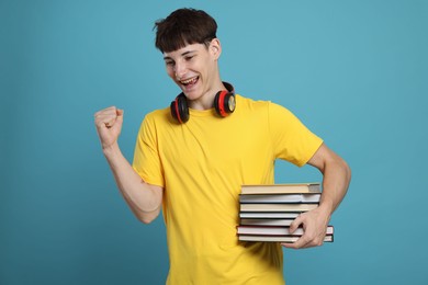 Photo of Happy student with books celebrating good exam result on light blue background