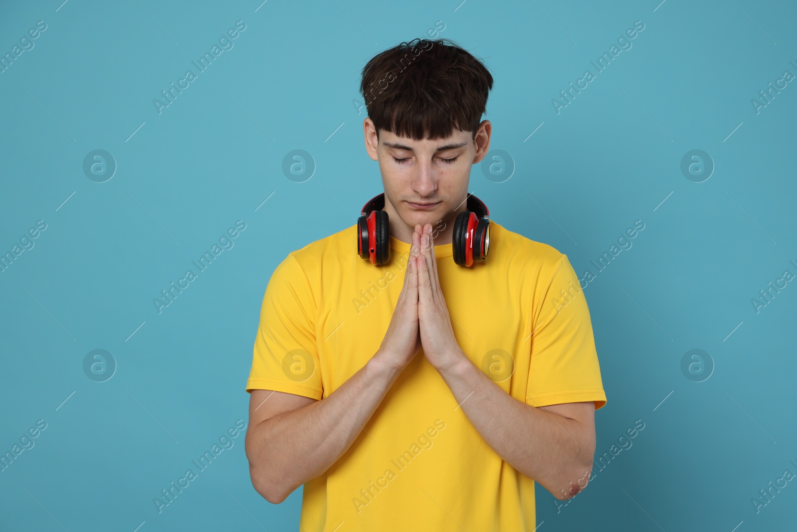 Worried student with clasped hands praying for good exam result on light blue background Photo of Worried student with clasped hands praying for good exam result on light blue background