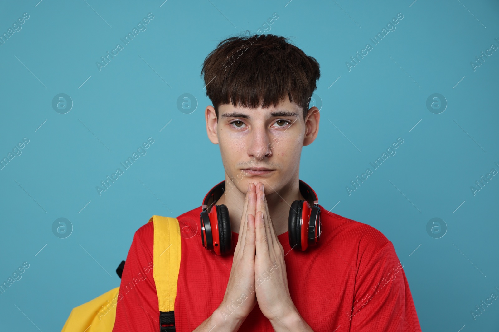 Worried student with clasped hands praying for good exam result on light blue background Photo of Worried student with clasped hands praying for good exam result on light blue background