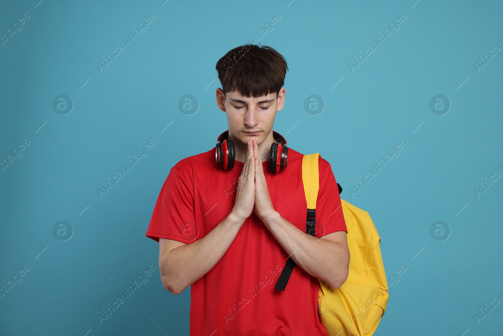 Worried student with clasped hands praying for good exam result on light blue background Photo of Worried student with clasped hands praying for good exam result on light blue background