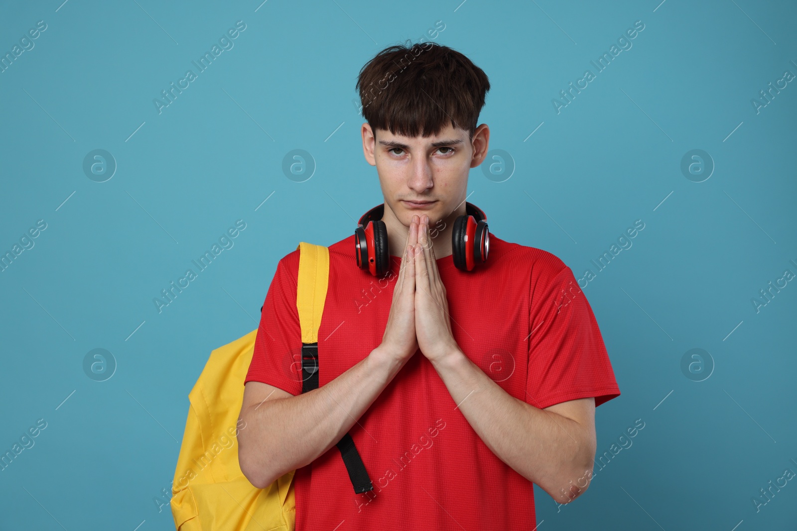 Worried student with clasped hands praying for good exam result on light blue background Photo of Worried student with clasped hands praying for good exam result on light blue background