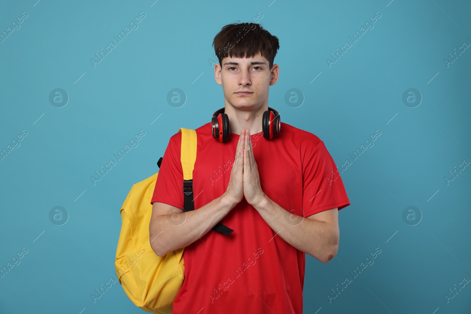 Worried student with clasped hands praying for good exam result on light blue background Photo of Worried student with clasped hands praying for good exam result on light blue background