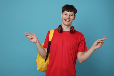 Photo of Happy student crossing fingers for good exam result on light blue background
