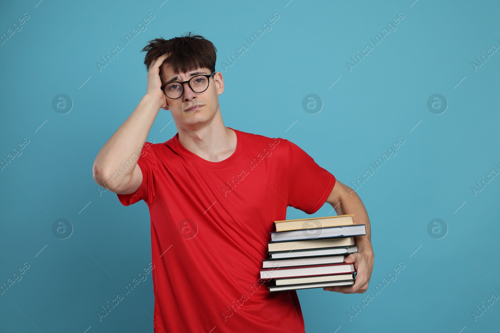 Exam result. Worried student with books on light blue background Photo of Exam result. Worried student with books on light blue background