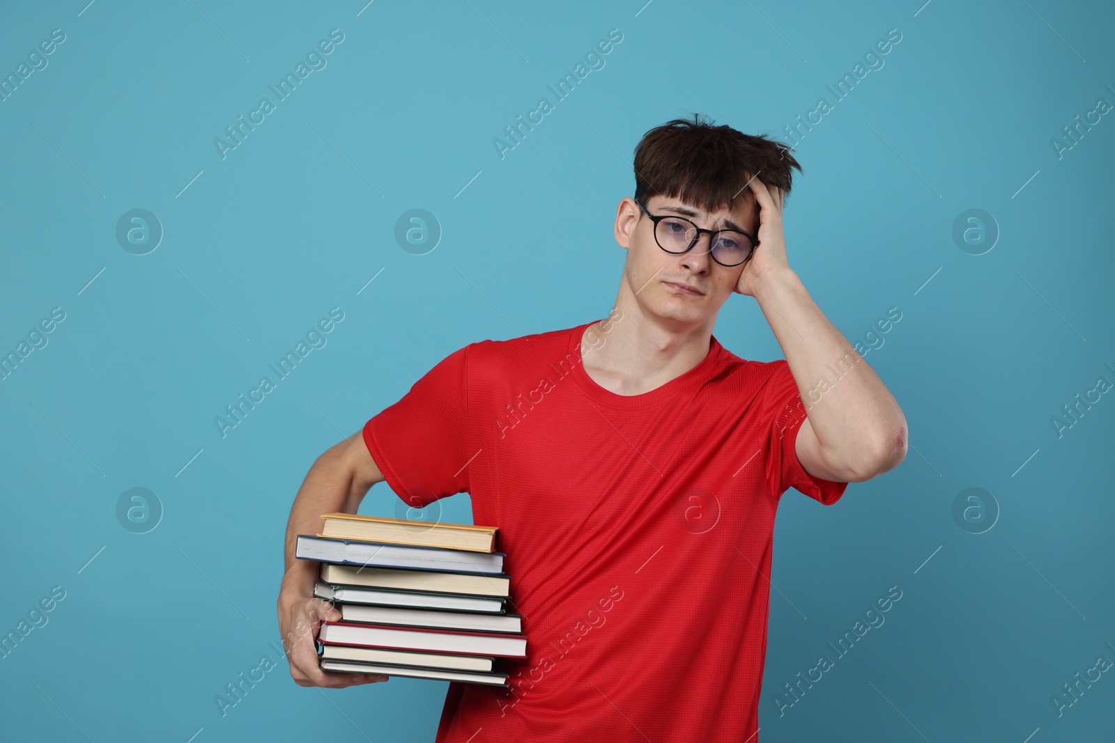 Exam result. Worried student with books on light blue background Photo of Exam result. Worried student with books on light blue background