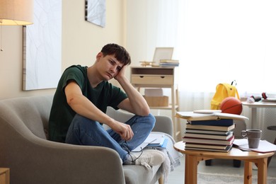 Photo of Tired student preparing for exam at table indoors