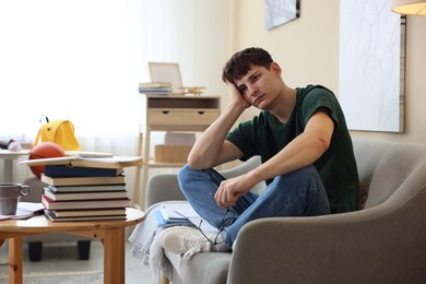 Photo of Tired student preparing for exam at table indoors