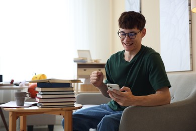 Photo of Happy student celebrating good exam result at table indoors