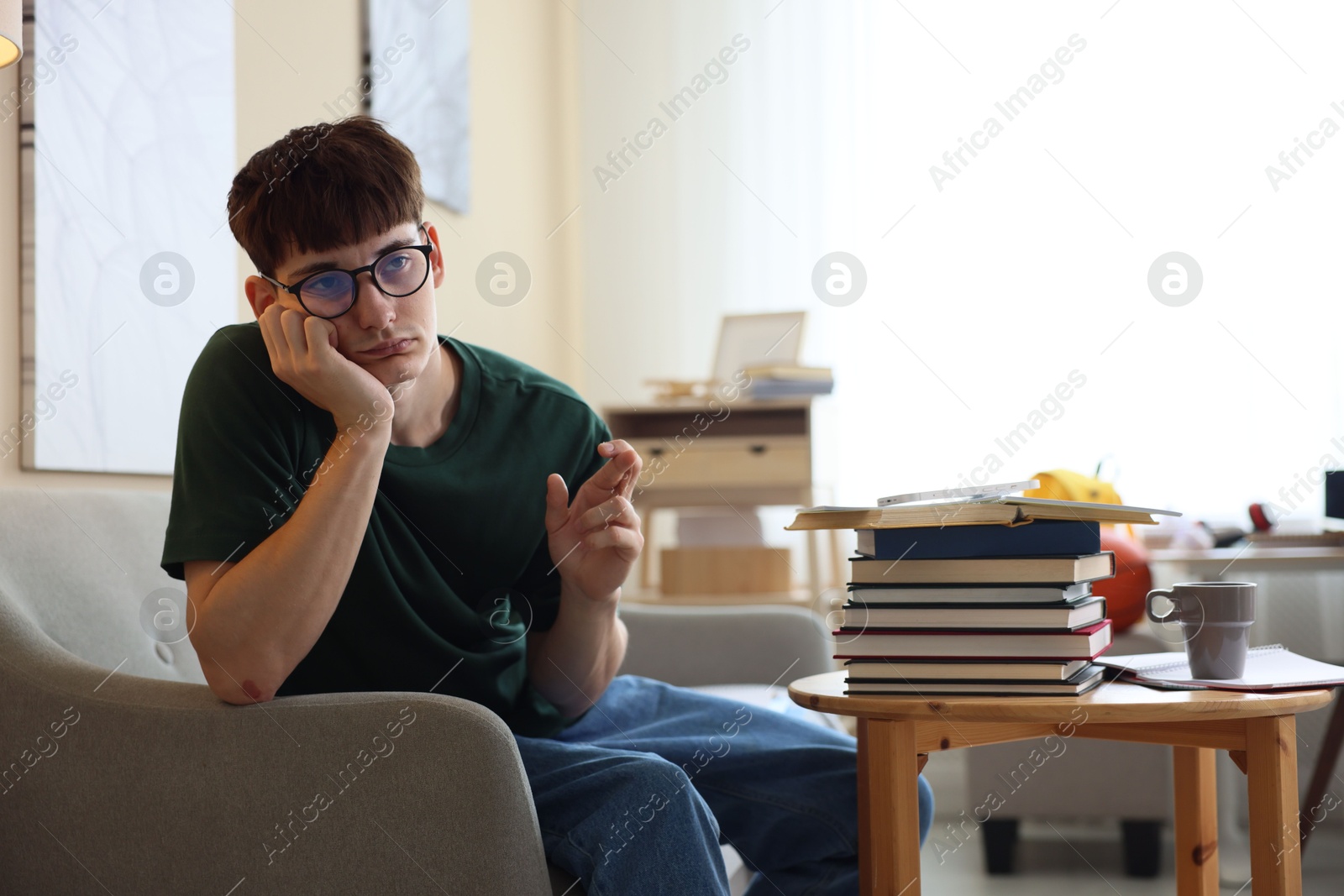 Worried student crossing fingers for good exam result at table indoors Photo of Worried student crossing fingers for good exam result at table indoors