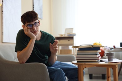 Photo of Worried student crossing fingers for good exam result at table indoors