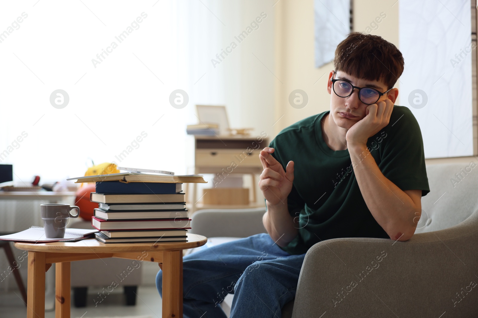 Worried student crossing fingers for good exam result at table indoors Photo of Worried student crossing fingers for good exam result at table indoors
