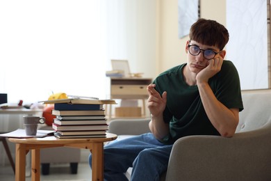 Photo of Worried student crossing fingers for good exam result at table indoors
