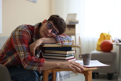 Photo of Tired student preparing for exam at table indoors