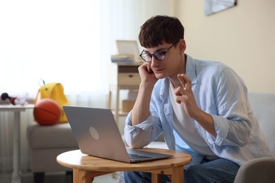 Photo of Worried student crossing fingers for good exam result at table indoors