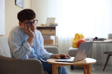 Photo of Tired student preparing for exam at table indoors