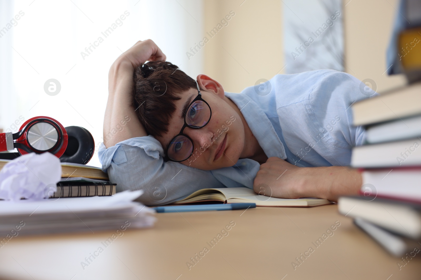 Tired student preparing for exam at table indoors Photo of Tired student preparing for exam at table indoors