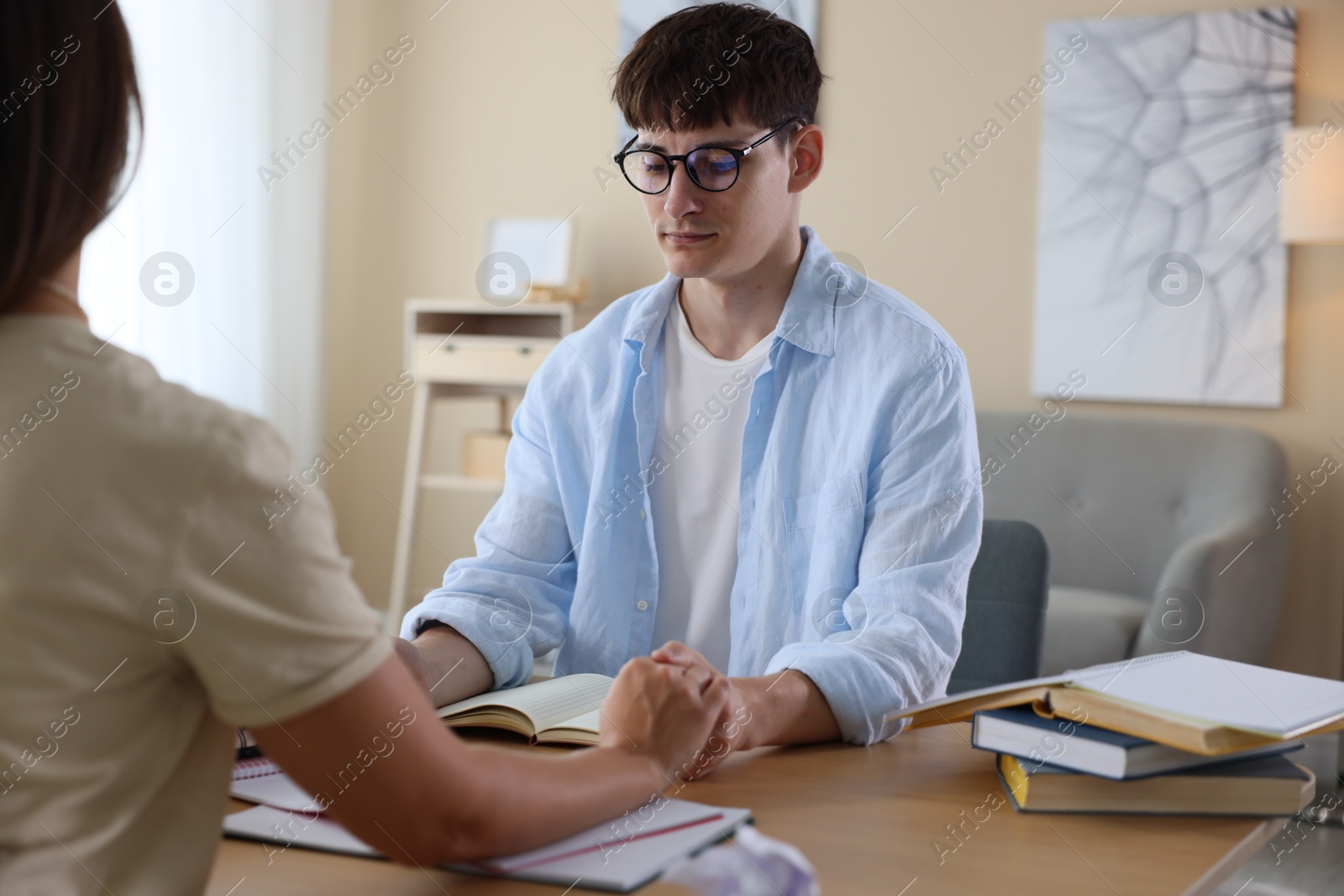 Students holding hands and praying for good exam result at table indoors Photo of Students holding hands and praying for good exam result at table indoors