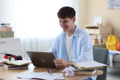 Photo of Happy student celebrating good exam result at table indoors