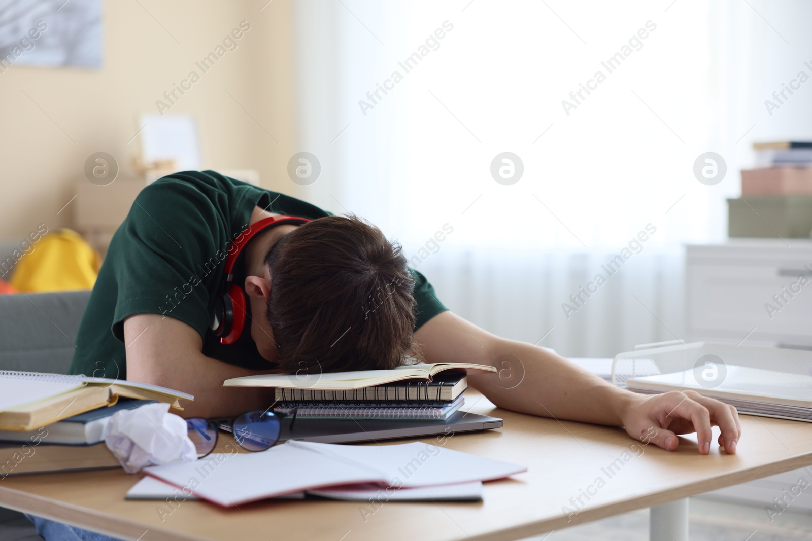 Tired student preparing for exam at table indoors Photo of Tired student preparing for exam at table indoors