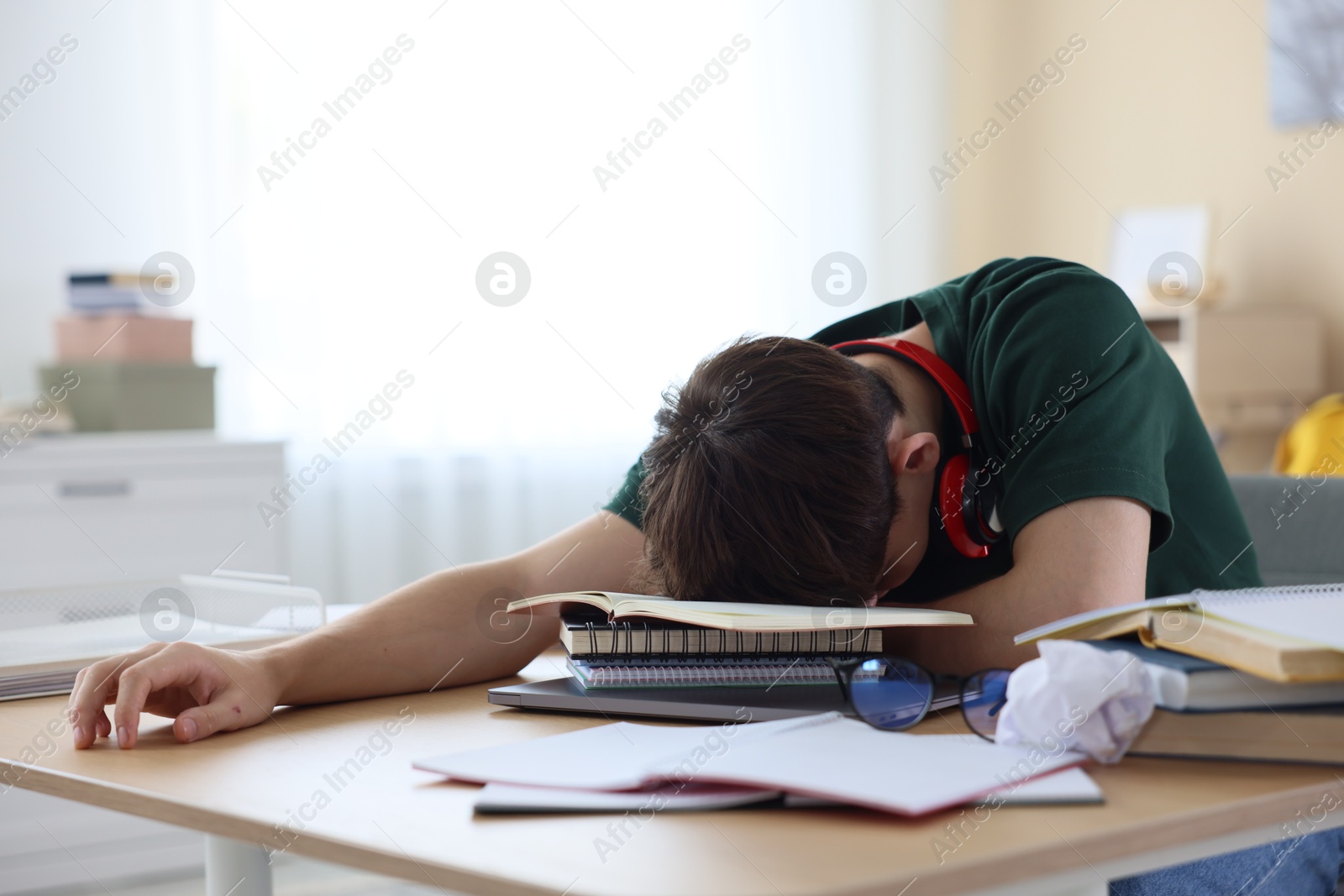 Tired student preparing for exam at table indoors Photo of Tired student preparing for exam at table indoors