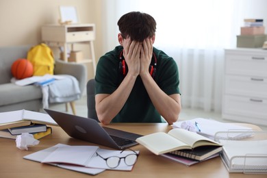 Photo of Tired student preparing for exam at table indoors