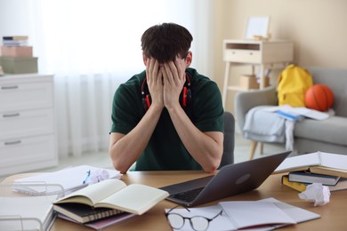 Photo of Tired student preparing for exam at table indoors