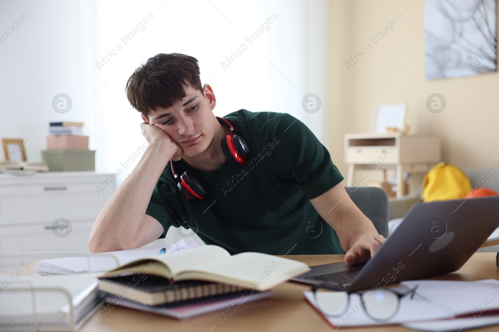 Tired student preparing for exam at table indoors Photo of Tired student preparing for exam at table indoors