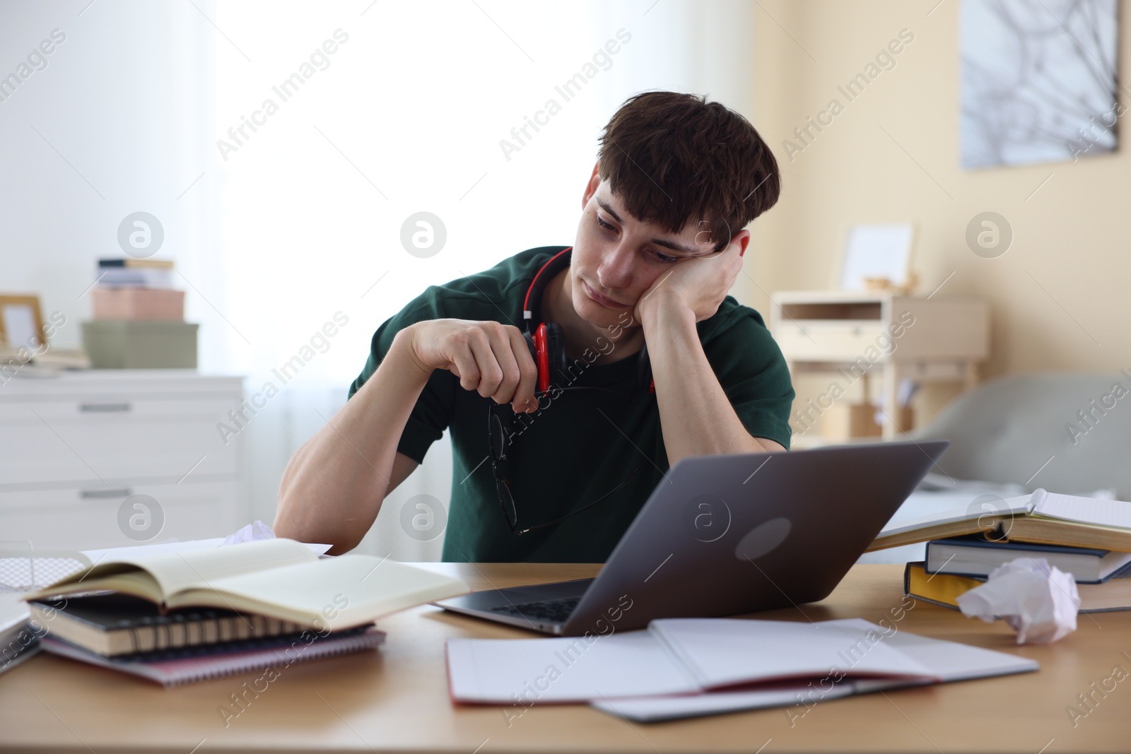 Tired student preparing for exam at table indoors Photo of Tired student preparing for exam at table indoors
