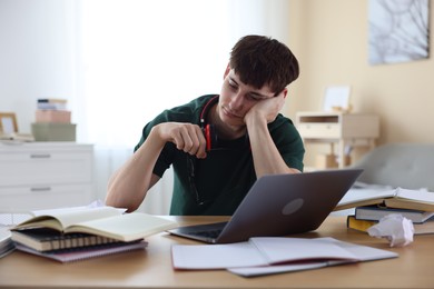 Photo of Tired student preparing for exam at table indoors